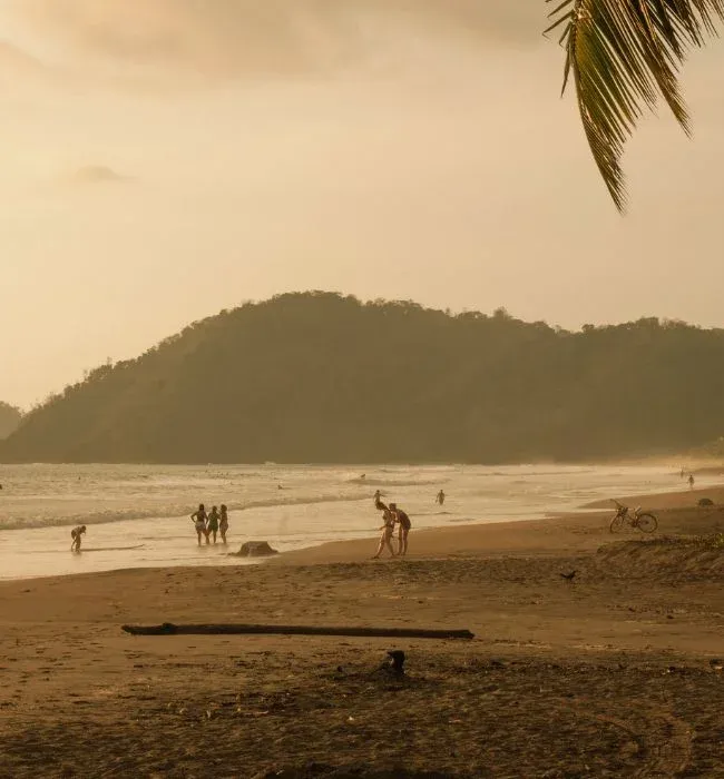 Coucher de soleil sur la plage de Jaco, promeneurs au bord de l'eau